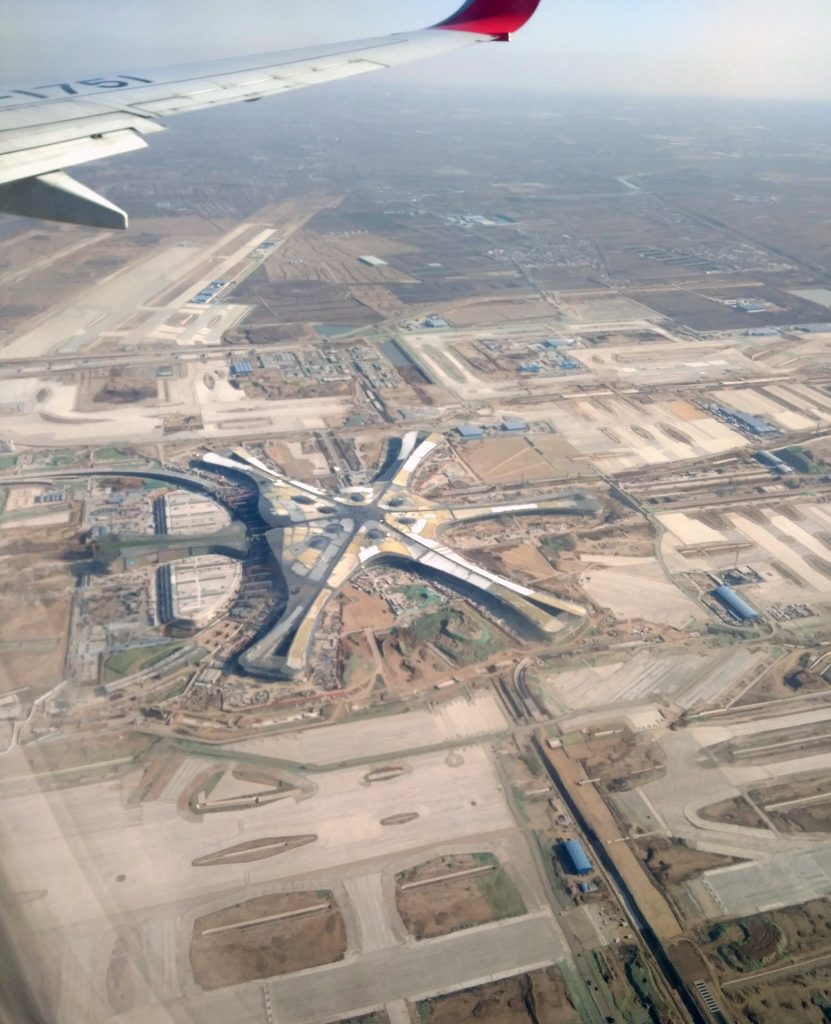 Aerial view of Beijing Daxing International Airport terminal from an airplane window