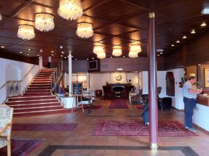 Hotel front desk reception counter with staff computer and lobby seating beyond