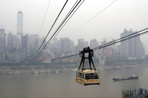 Yangtze River Cableway cabin crossing above the river with Chongqing bridges and hills beyond