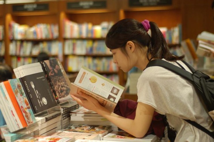 Visitor reading among bookshelves in a Taipei bookstore