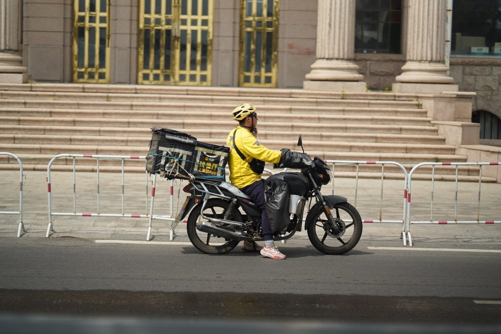 Food delivery rider on an electric scooter with insulated bag on a Chinese city street