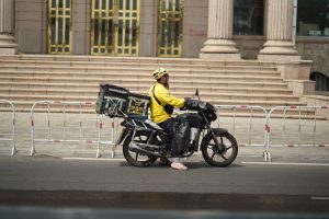 Food delivery rider on an electric scooter with insulated bag on a Chinese city street