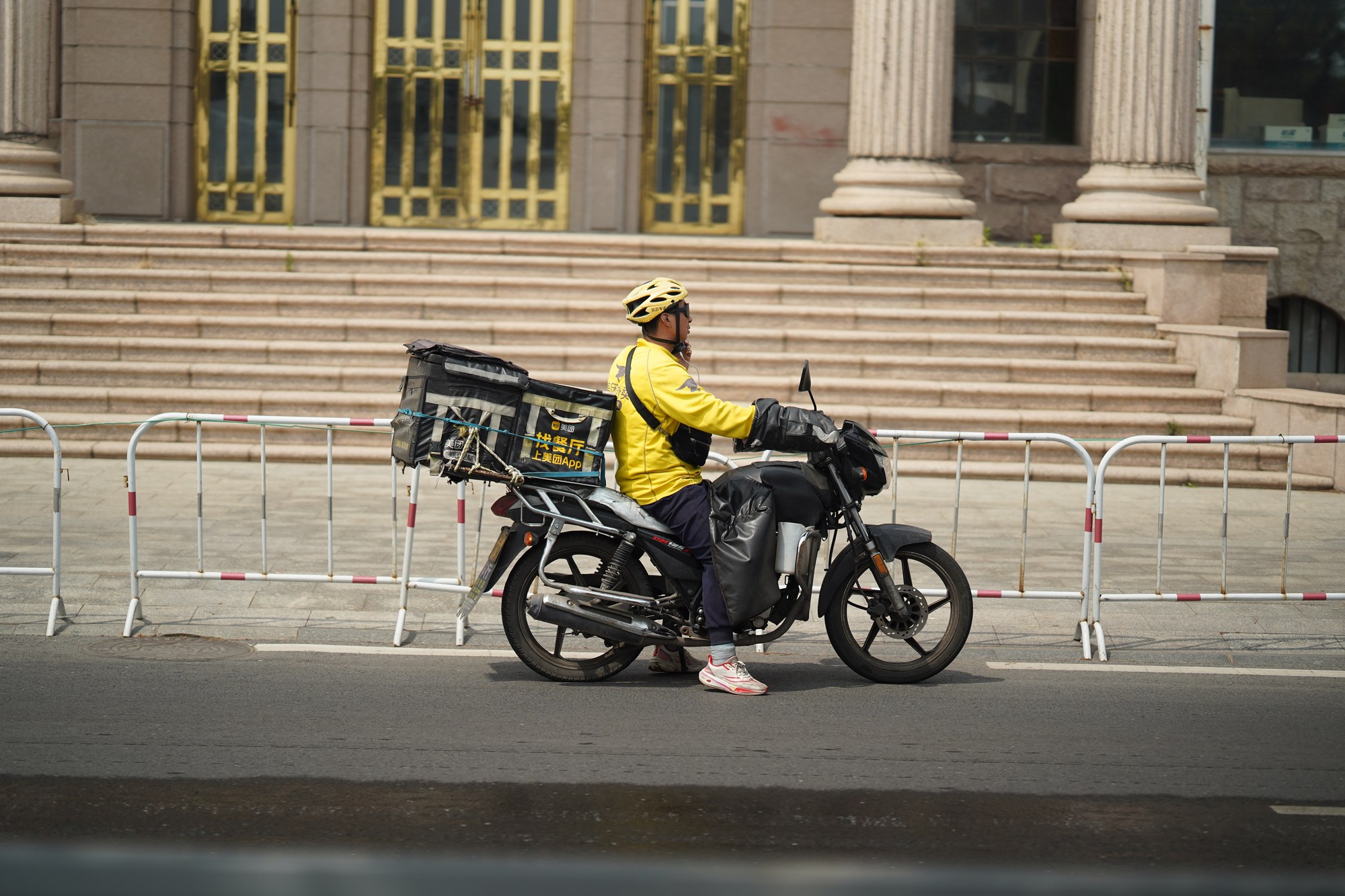 Food delivery rider on an electric scooter with insulated bag on a Chinese city street