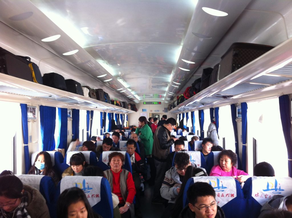 Interior of a China Railway hard-seat YZ25T carriage with blue seats and overhead racks