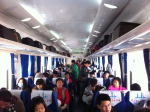 Interior of a China Railway hard-seat YZ25T carriage with blue seats and overhead racks