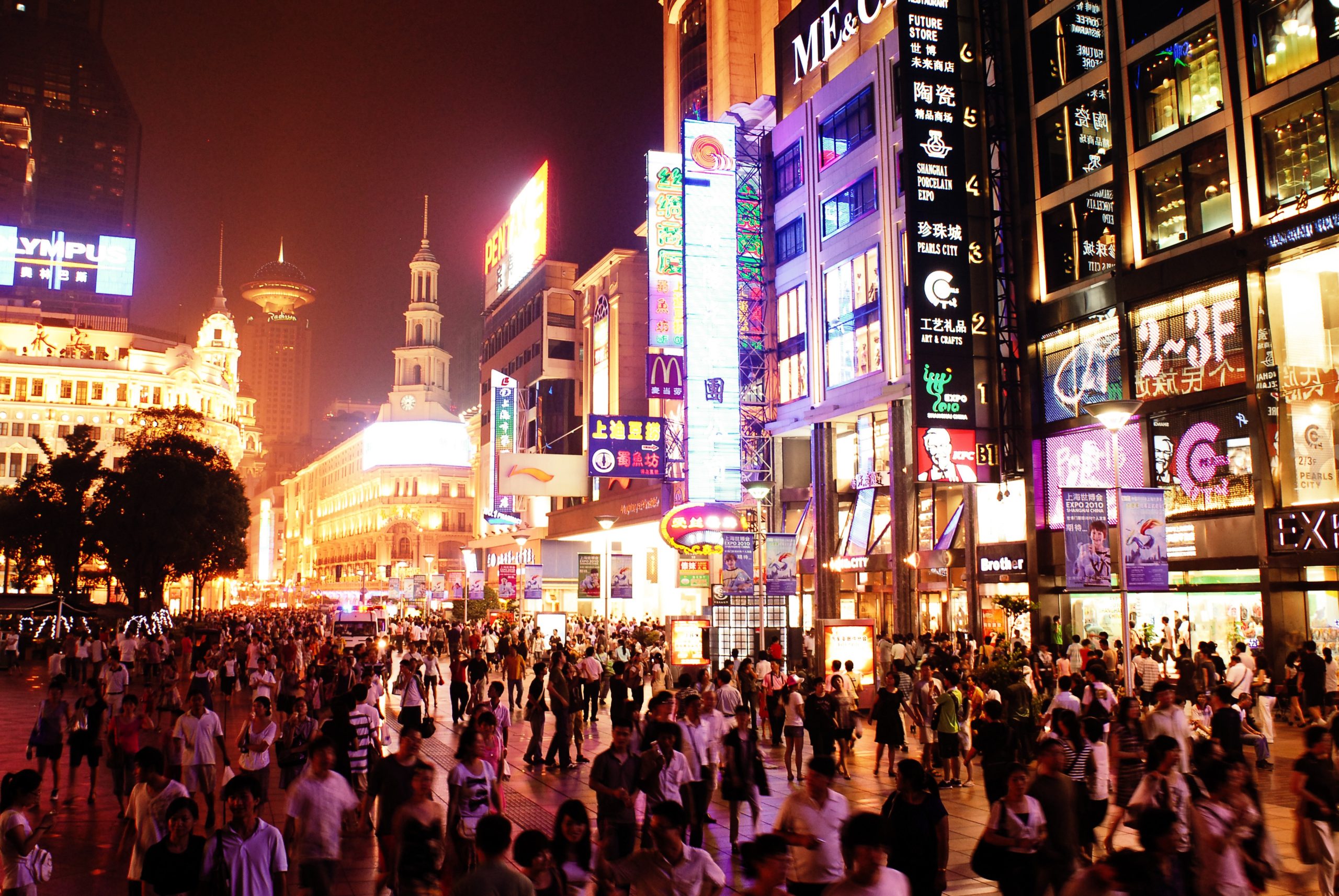Neon-lit Shanghai street at night with pedestrians and glowing shop signs