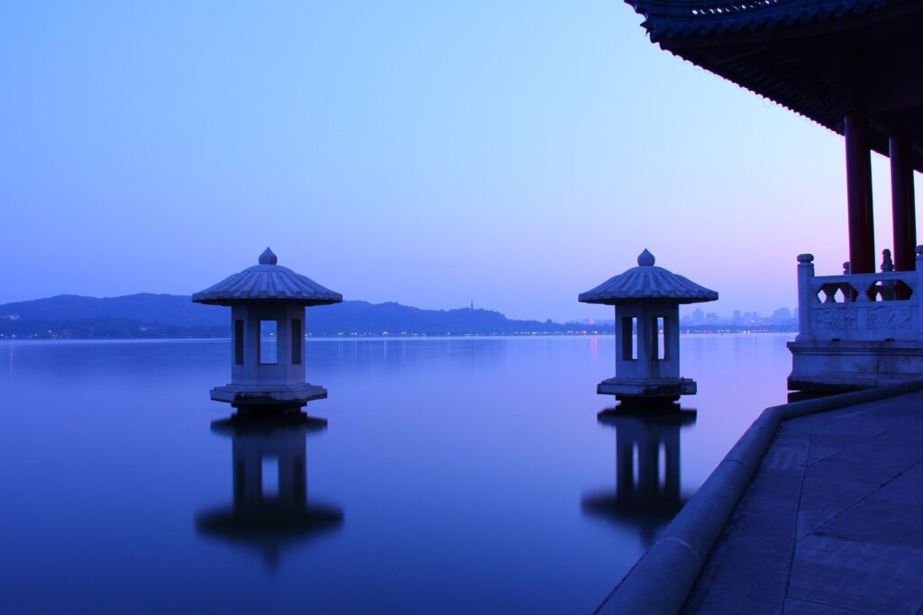 Autumn moon over calm West Lake with lakeside lights in Hangzhou