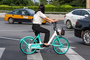 Cyclist on a shared DiDi bike waiting at a Beijing intersection
