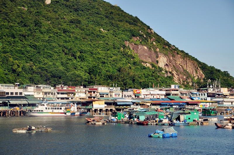 Ferry and fishing village along a green Hong Kong outlying island shore