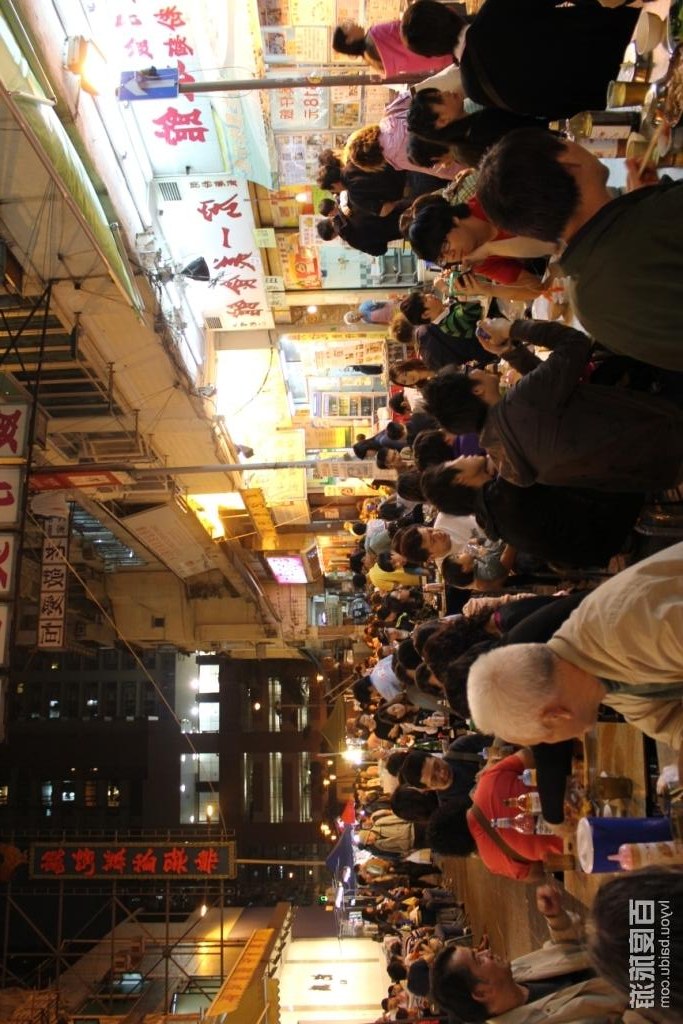 Outdoor dining tables along a neon Hong Kong night market street