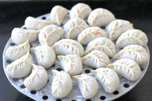 Plate of Chinese jiaozi dumplings with dipping sauce on a wooden table