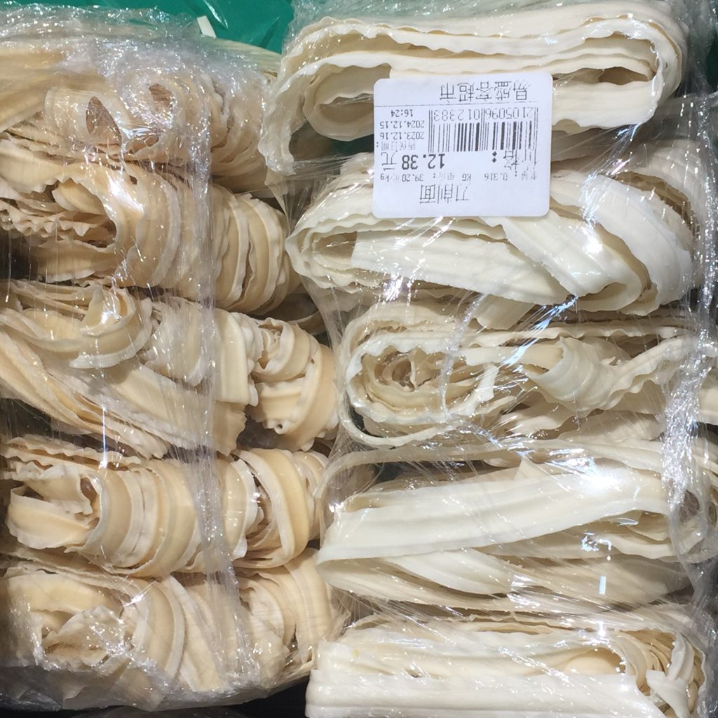 Bowl of Chinese knife-cut noodles with sauce and chopped toppings