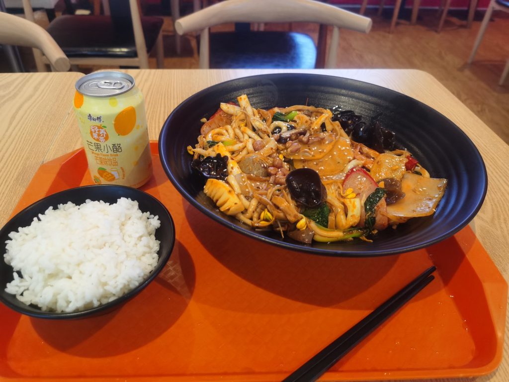 Mala xiangguo spicy dry pot served with a bowl of white rice and a drink