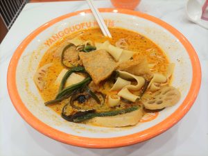 Bowl of malatang spicy hot soup with vegetables noodles and toppings