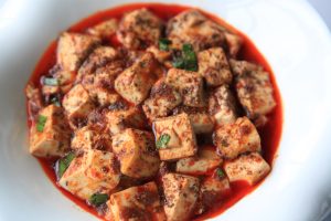 Plate of mapo tofu with minced meat and chili oil over soft tofu cubes