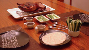Sliced Peking duck with crispy skin arranged on a plate ready to wrap in pancakes