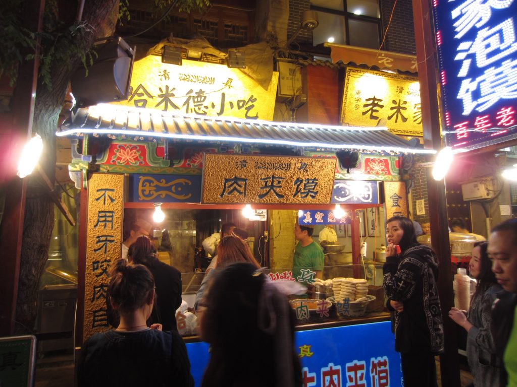 Close-up of a Xi'an-style roujiamo meat sandwich with shredded braised pork in a cracked flatbread