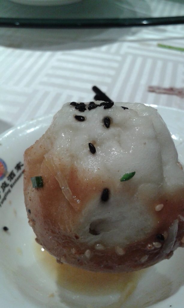 Pan-fried Shanghai shengjianbao pork buns with sesame seeds in a cooking pan