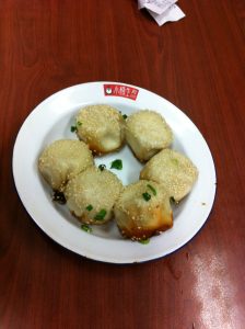Fresh pan-fried shengjianbao pork buns with sesame and scallion on a plate in Shanghai