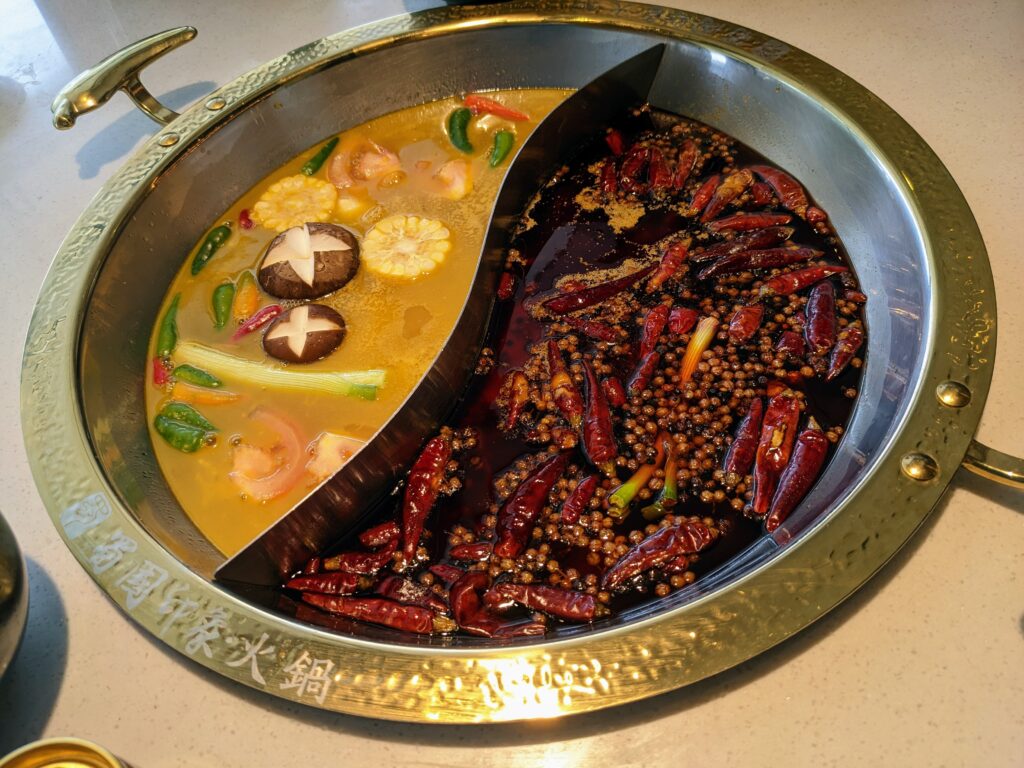Divided yuanyang hotpot with mild broth on one side and spicy mala chili broth on the other