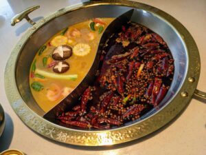 Divided yuanyang hotpot with mild broth on one side and spicy mala chili broth on the other