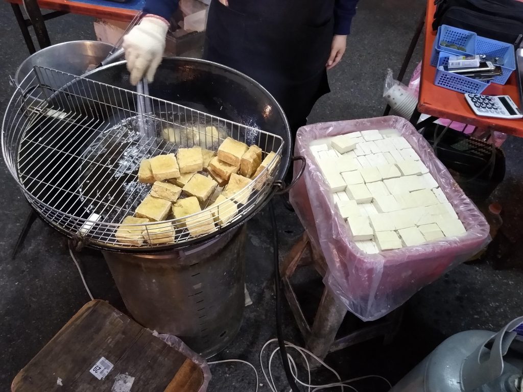 Plate of fried stinky tofu with toppings at a Chinese night market stall