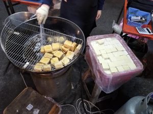 Plate of fried stinky tofu with toppings at a Chinese night market stall