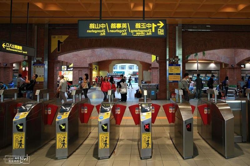 Commuters passing through Taipei MRT ticket gates in a brick-arched station