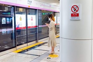 Passenger using a smartphone while waiting at a Beijing metro station platform