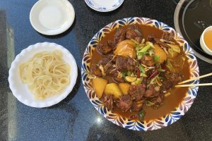 Xinjiang big plate chicken (dapanji) with wide noodles in a large shared platter